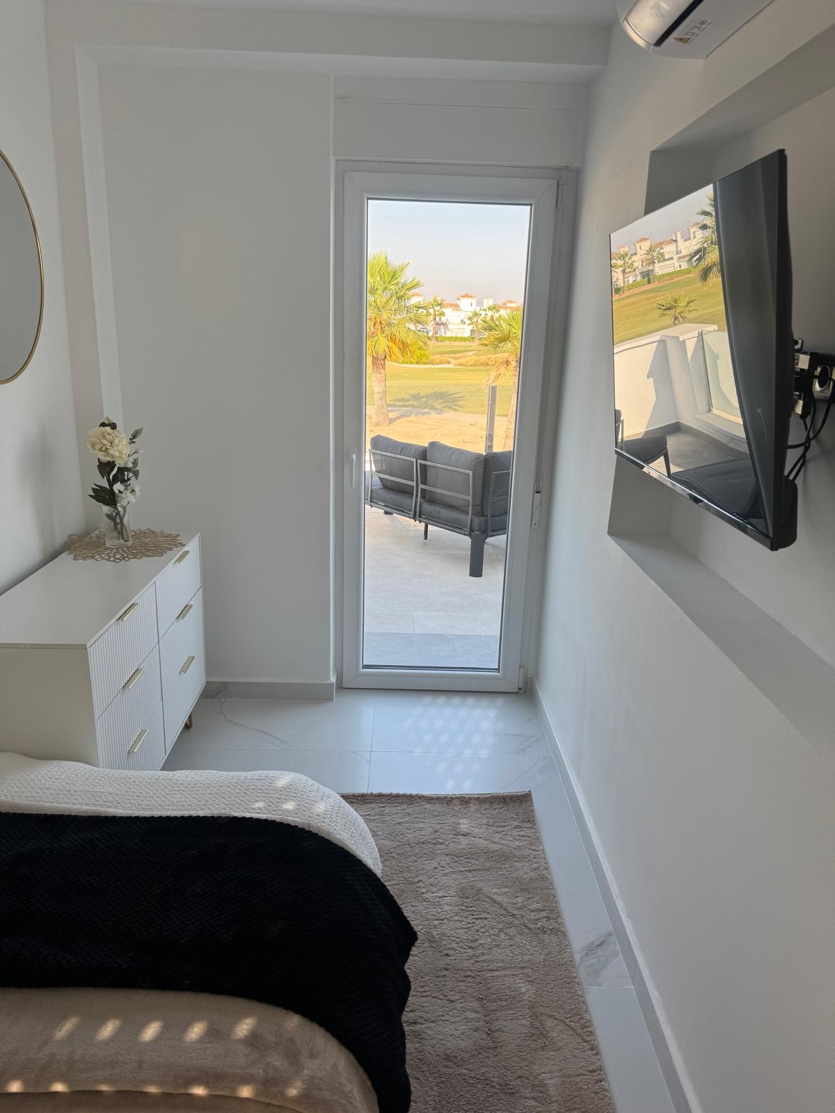Third bedroom's private terrace door opening onto seating with a direct view over the golf course